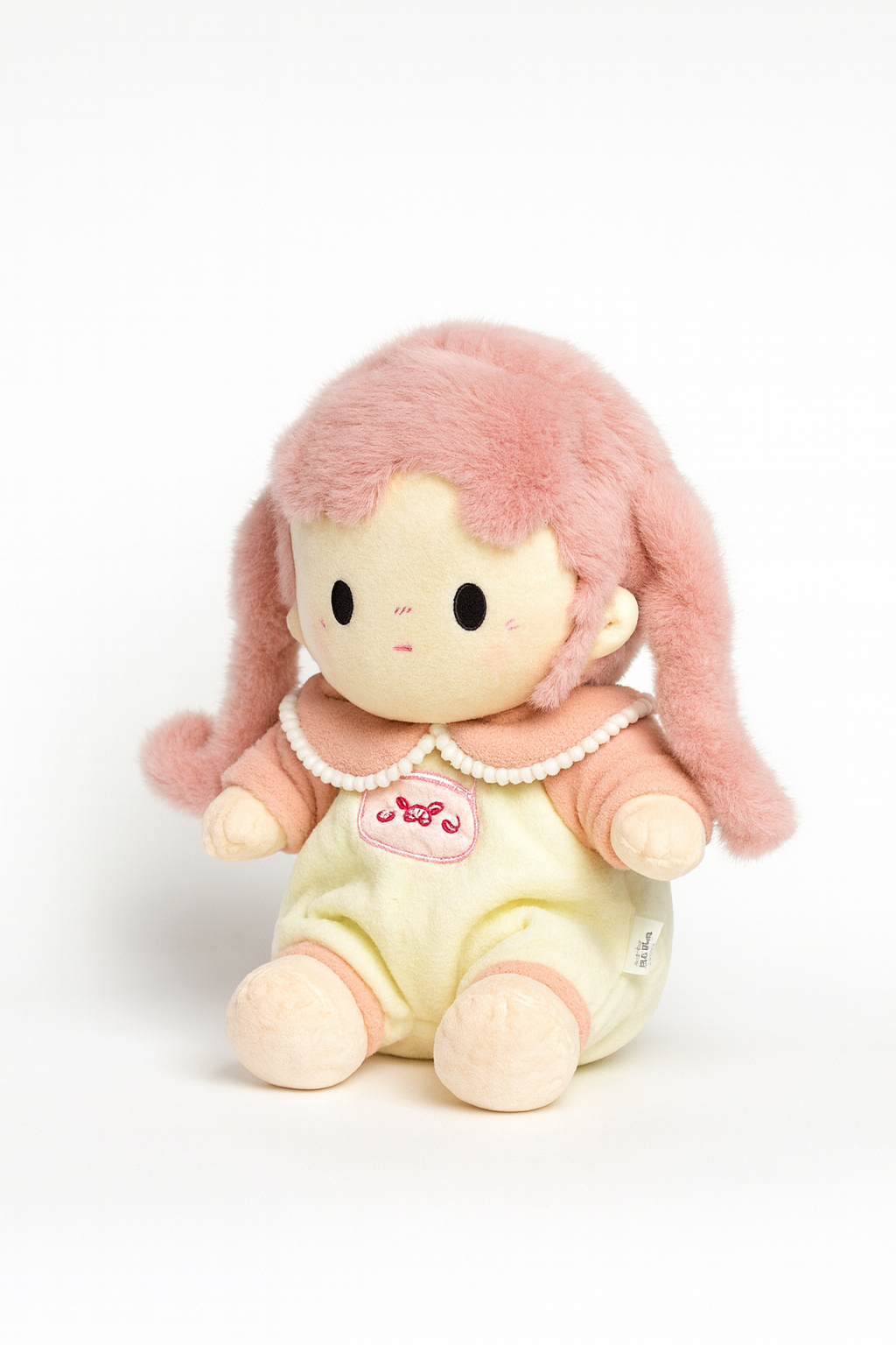 Plush toy with pink hair and a heart emblem on a white background